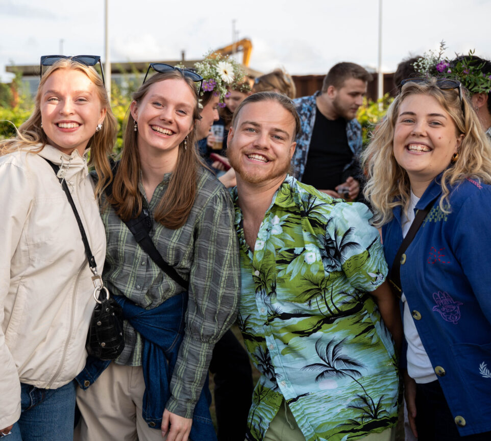 En gruppe unge mennesker står sammen og smiler mod kameraet.