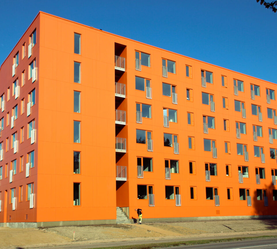 På billedet fremgår et stort, orange bygningskompleks med ungdomsboliger.