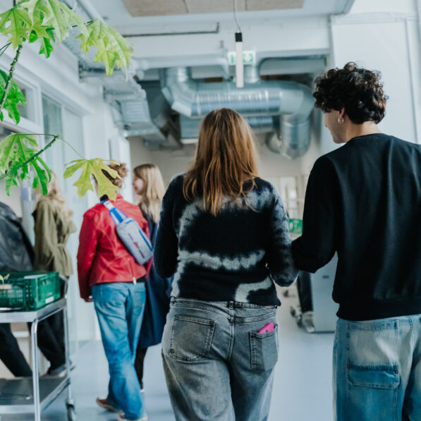 En ung mand og ung kvinder går efter en række af andre unge gennem Designskolen Kolding.