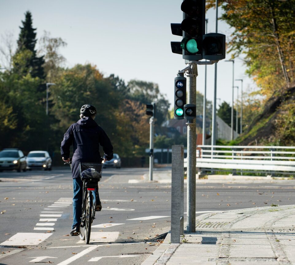 En cyklist har fået grønt lys og skal til at køre gennem et lyskryds med modkørende billister.